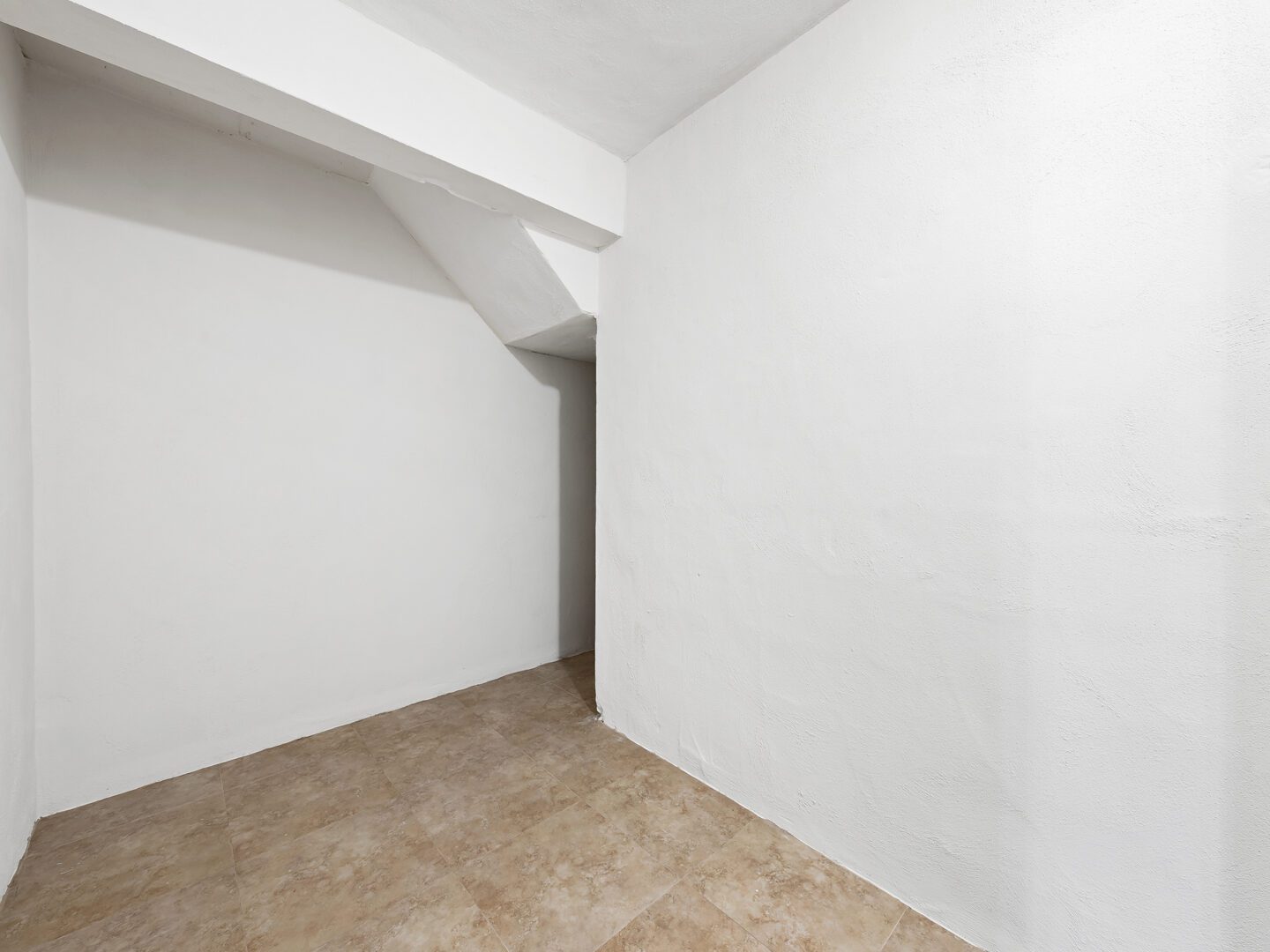 Empty room with white walls and tiled floor.