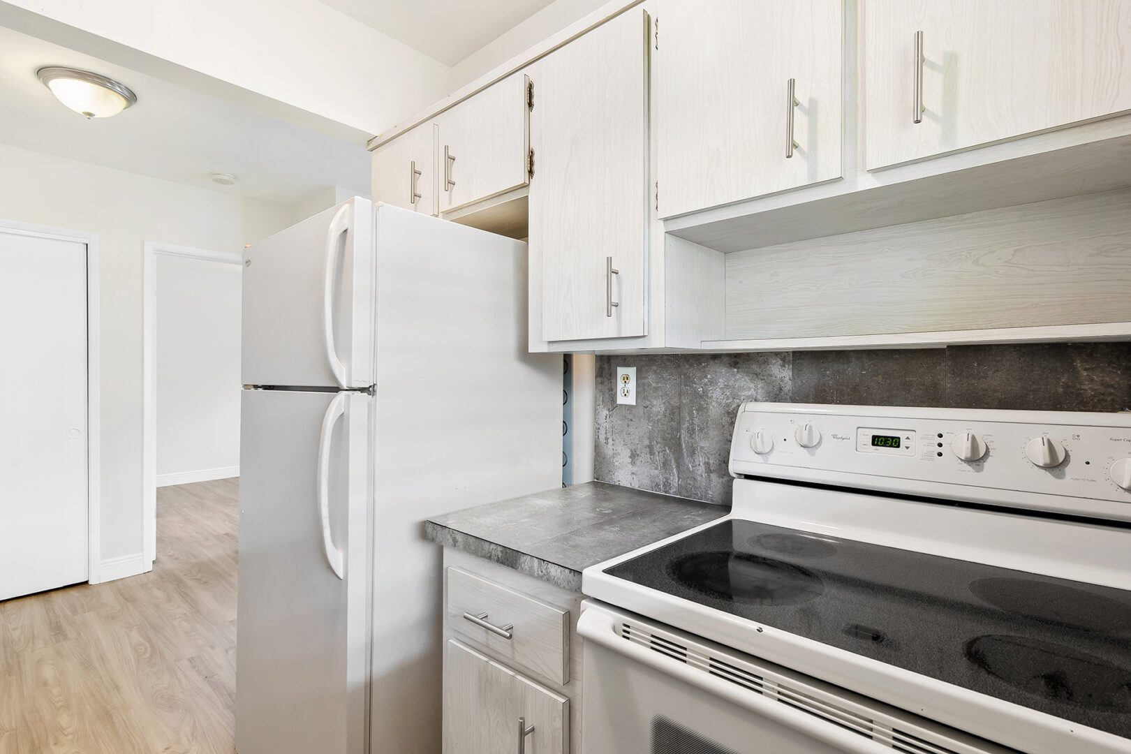 Modern kitchen with white cabinets and appliances.
