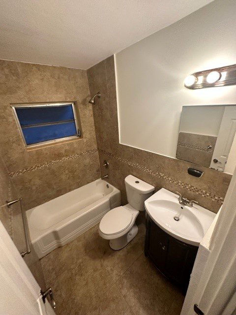 Compact bathroom with bathtub, toilet, and sink under warm lighting.