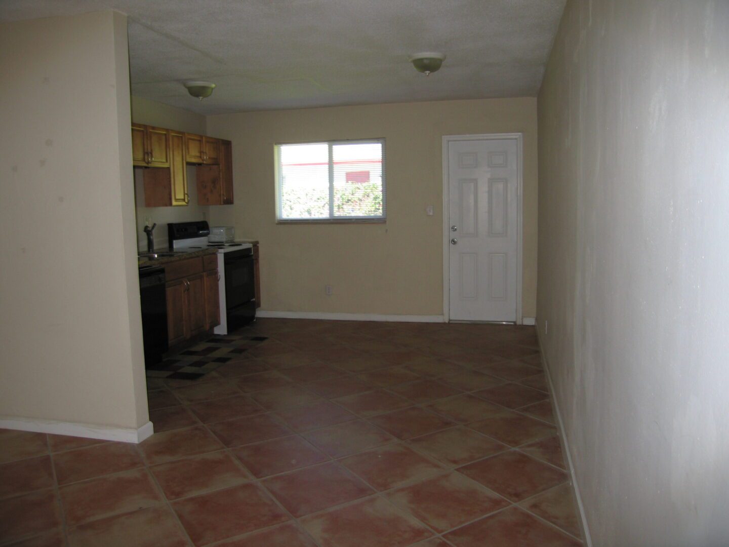 Empty kitchen and dining area with tiled floors and a window.