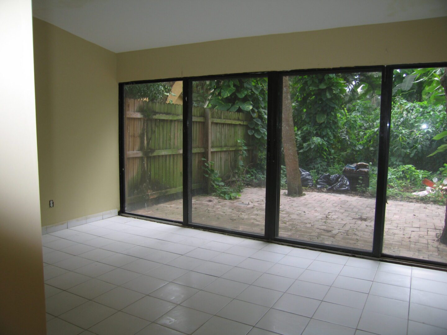 Empty room with large sliding glass doors overlooking a backyard.