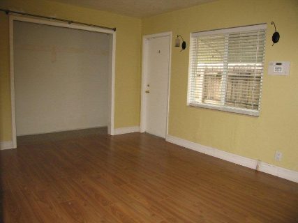 Empty room with wooden flooring and yellow walls.
